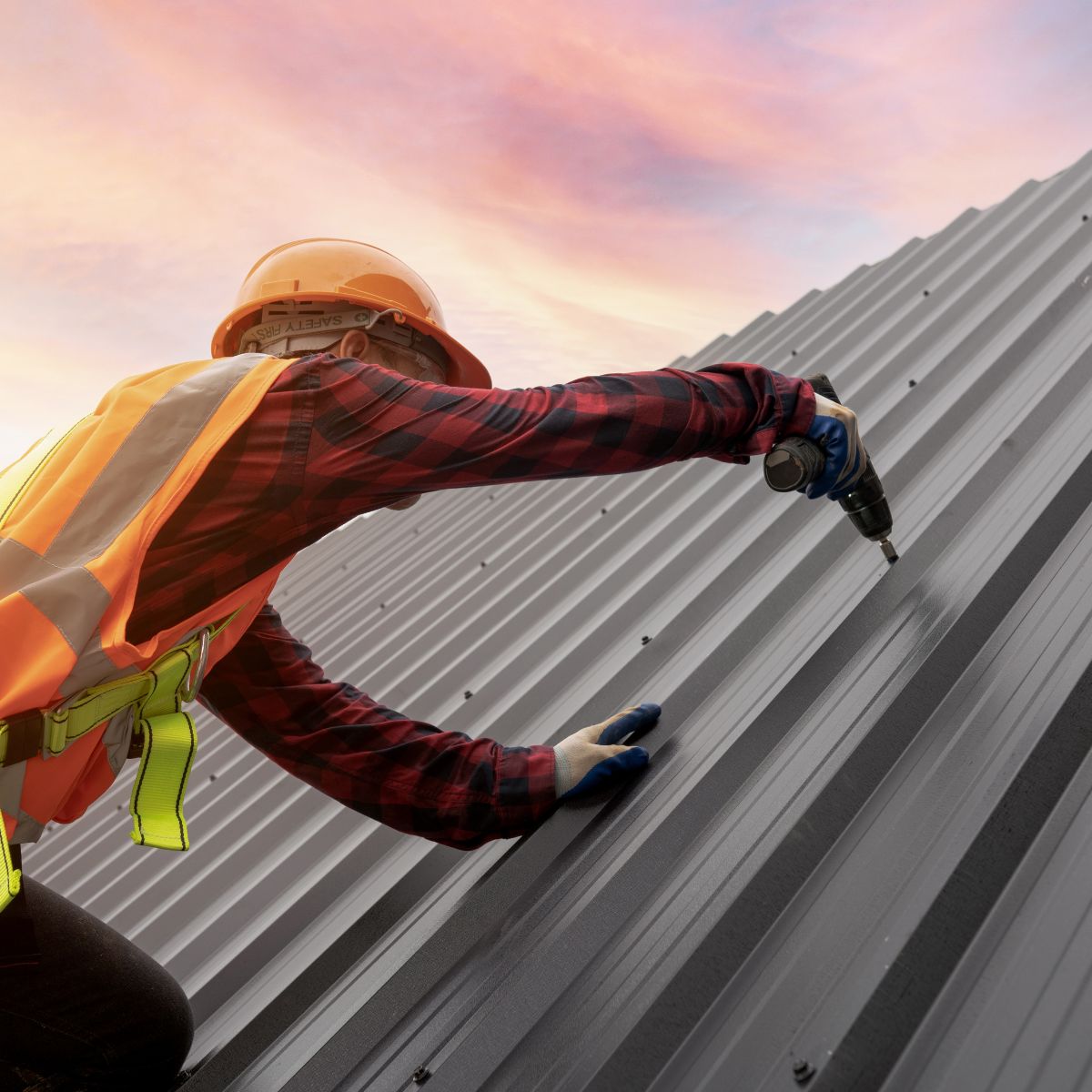A metal roofing contractor with Triumph Roofing installing a metal panel with a bolt.